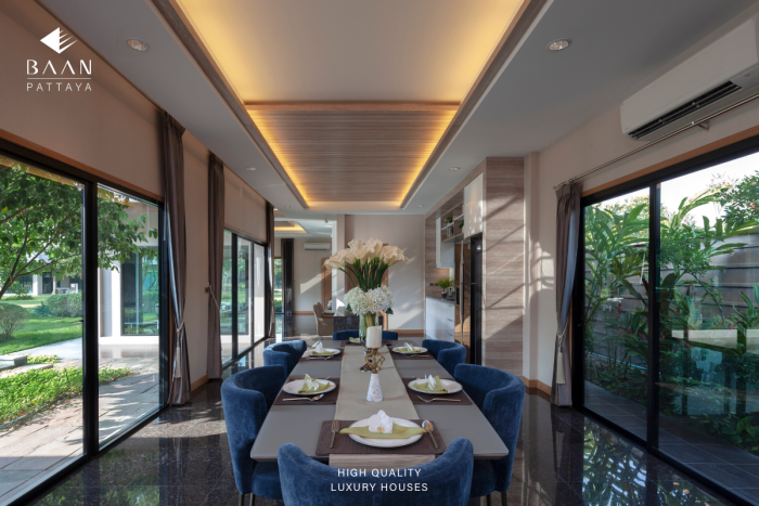 Baan Pattaya 5 outdoor swimming pool reflecting the modern house, with a family in the garden.