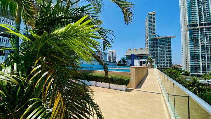 Laguna Heights rooftop terrace with swimming pool, palm trees, and city skyline in the background.