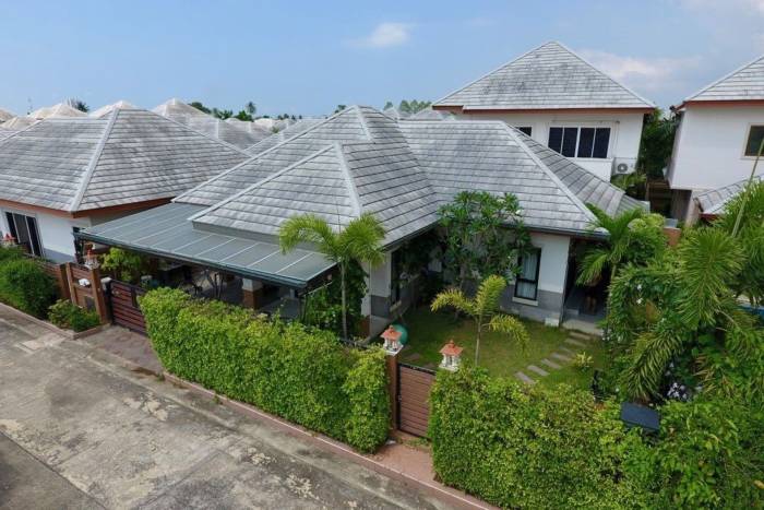 Baan Dusit Pattaya Park single-story house with a covered carport, small front yard, and a green hedge fence.