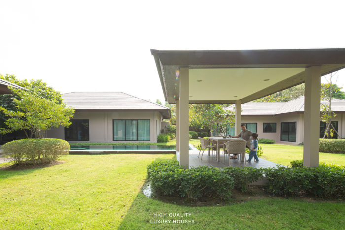 Baan Pattaya 5 spacious living room with a grey sofa, coffee table, wall-mounted TV, and garden view.