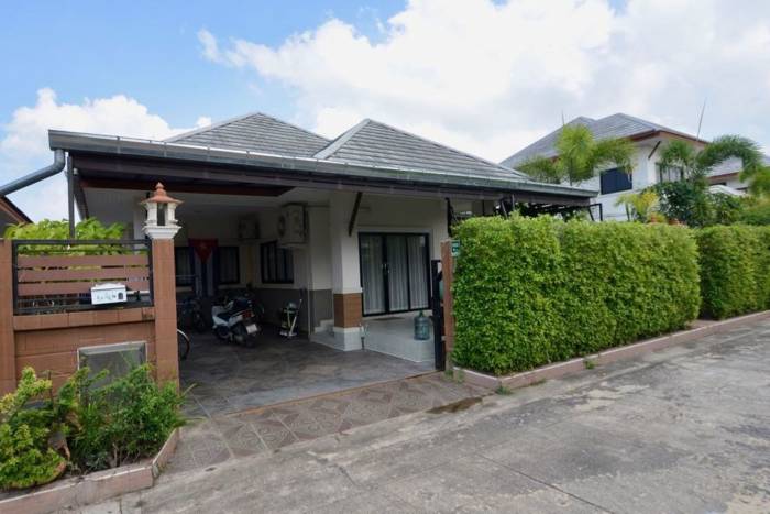 Baan Dusit Pattaya Park entrance sign made of dark stone with reflective silver lettering and green landscaping.