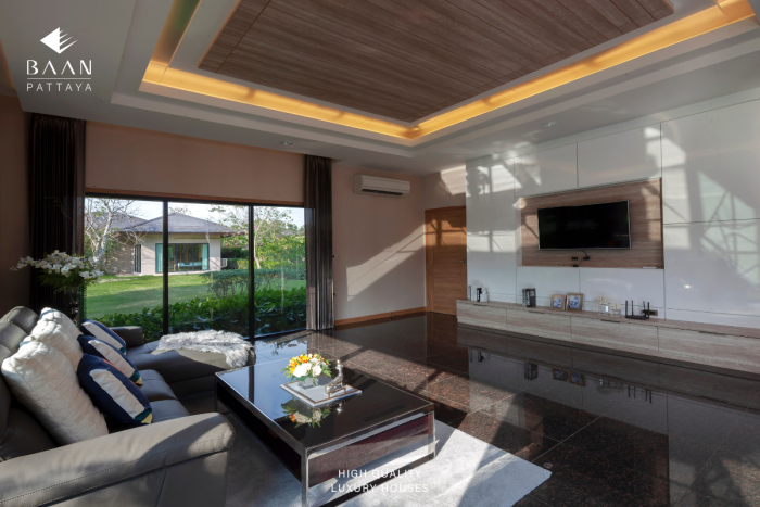 Baan Pattaya 5 elegant dining room with a long table, blue chairs, and large windows overlooking the garden.