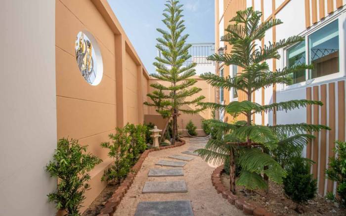 Narita Villa bedroom with a large bed, wood paneling, and sliding glass doors opening to a private pool.