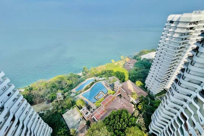 Royal Cliff Garden aerial view of two white condo towers, multiple pools, and lush coastline by the ocean.
