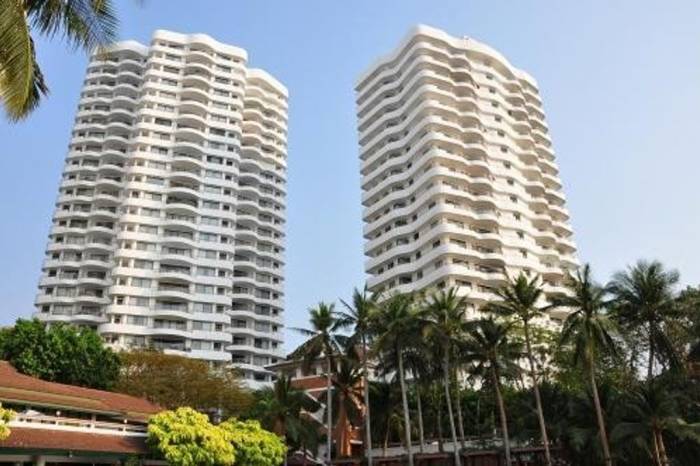 Royal Cliff Garden two white high-rise condo buildings with wavy balconies, palm trees, and lush greenery.