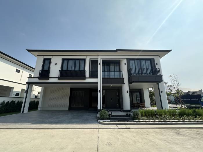 Chieftain contemporary two-story house with white exterior, black accents, a covered entrance, and a paved driveway.