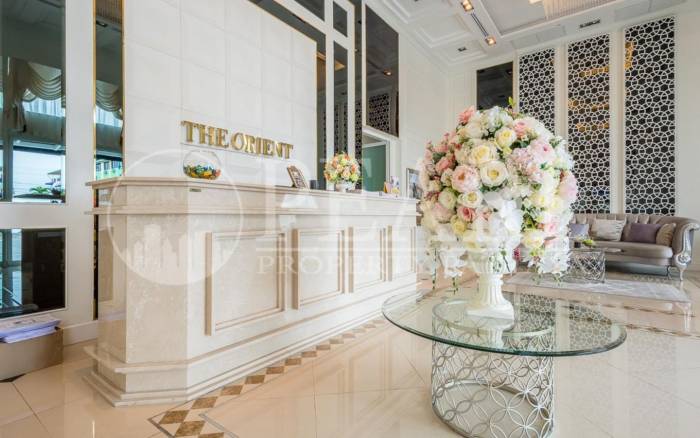 The Orient Resort & Spa: Elegant reception desk in the lobby with a large floral arrangement and stylish seating area.