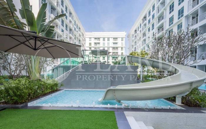 The Orient Resort & Spa: Outdoor swimming pool area featuring a water slide, sun loungers, and modern white buildings.