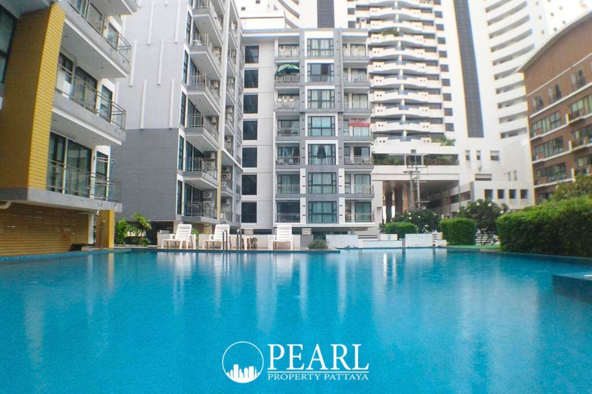 Neo Condo exterior view of the building's entrance, showing a drive-through area and surrounding greenery.