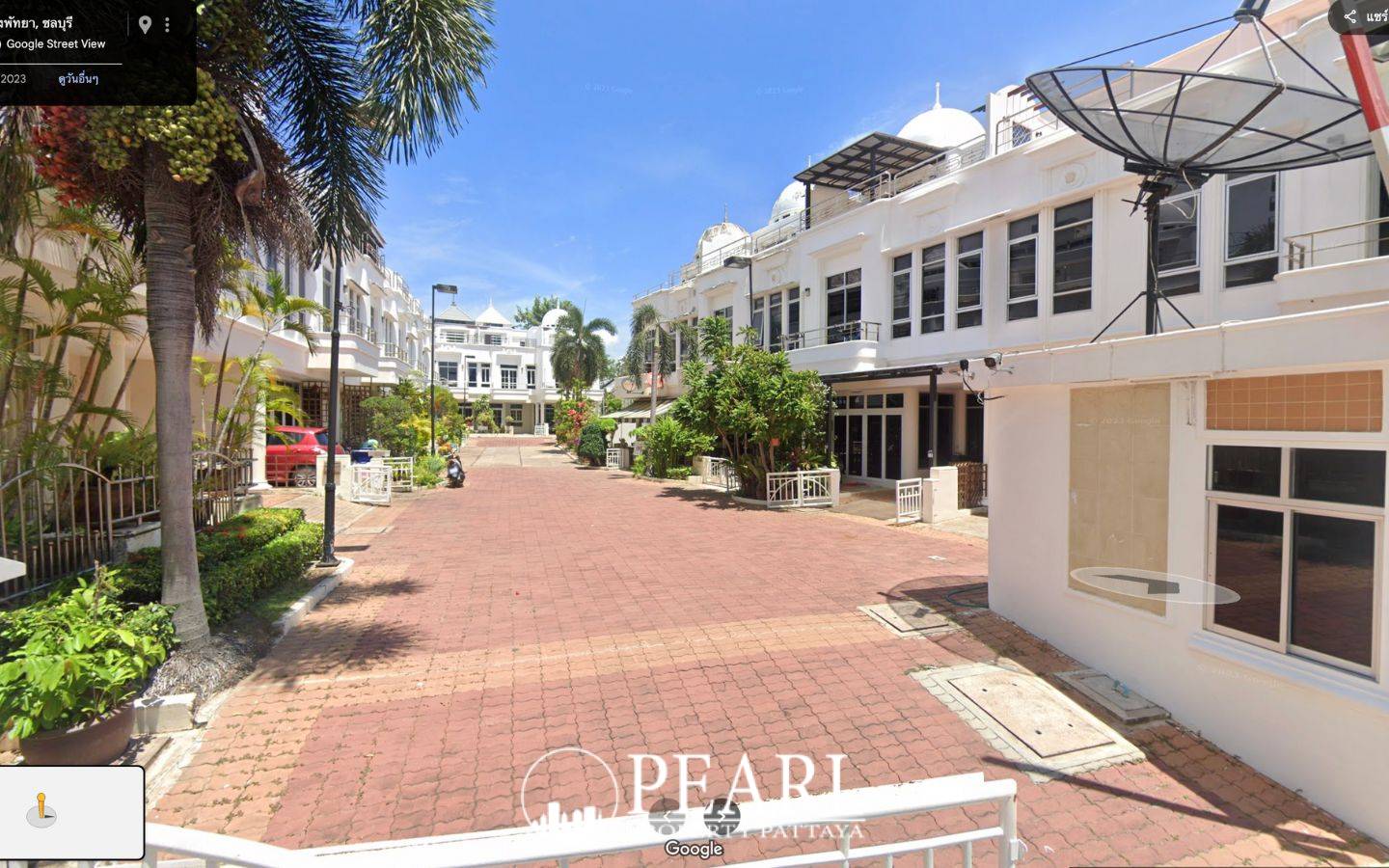 Wongamat Exclusive Place street view of the paved road leading into the residential complex with palm trees.