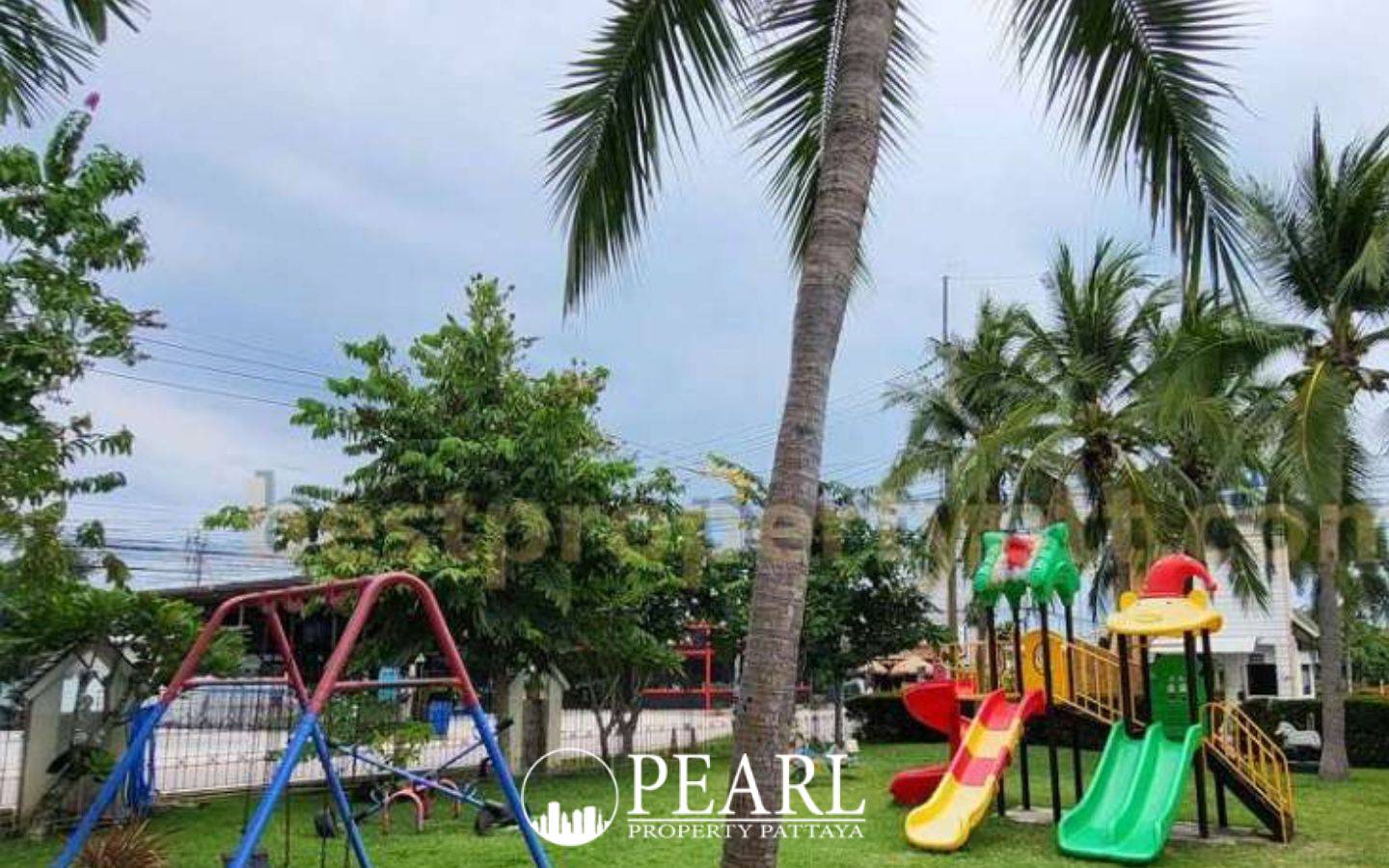 Central Park 4 main entrance gate with a guardhouse, 'Central Park' sign, palm trees, and houses in the background.