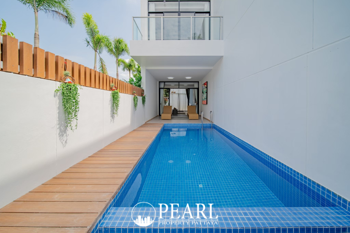 Maxx Pattaya modern white villas with large windows, surrounded by lush green tropical landscaping and palm trees.