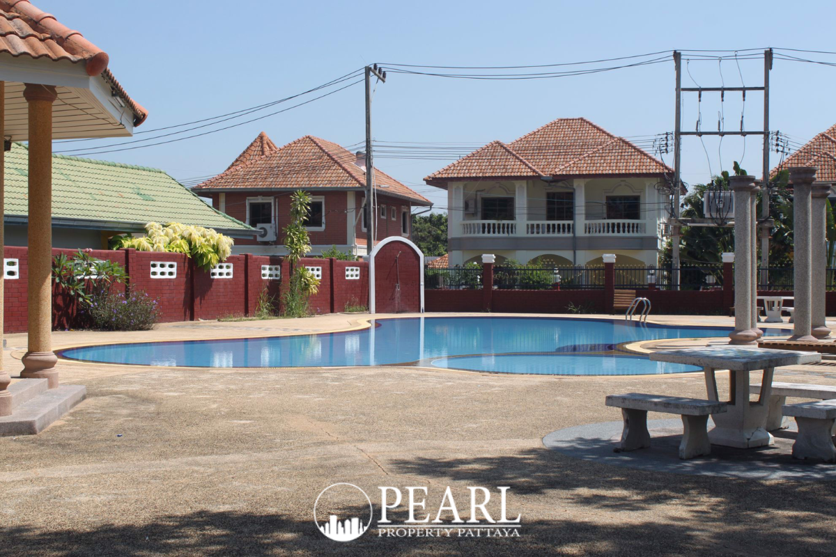 Grand Tanyawan Home large community swimming pool with houses and blue sky in the background.