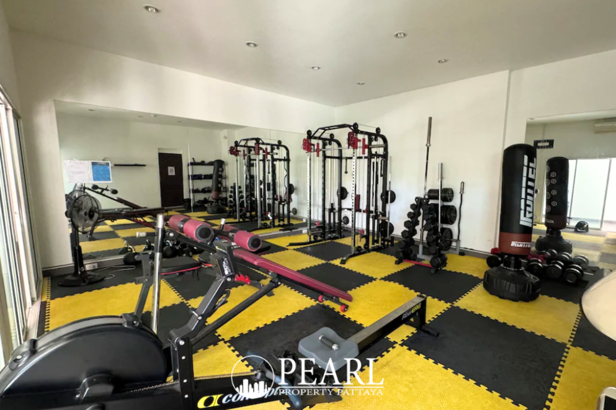 The Club House outdoor swimming pool with blue mosaic tiles, surrounded by a paved deck, tropical plants, and a white swan float.