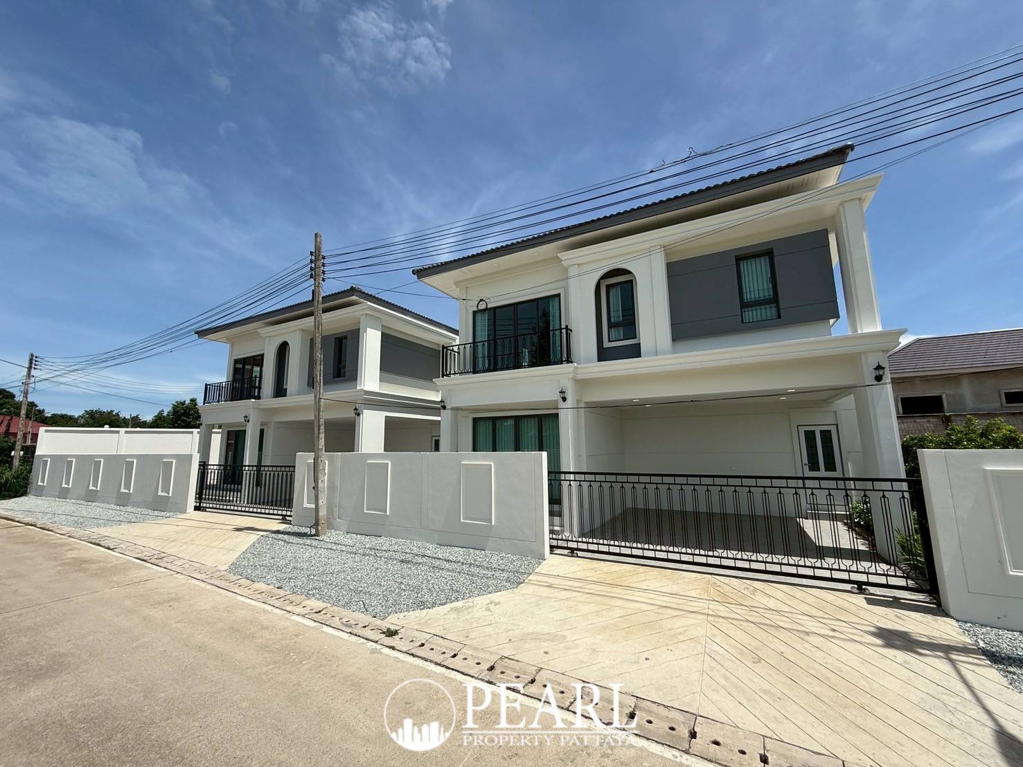 Spring Town Pool Villa Pattaya exterior view of two modern houses with gray and white facades under a blue sky.