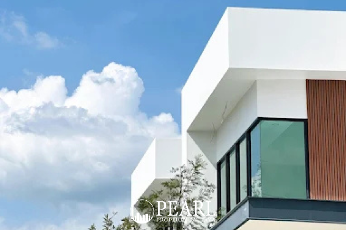 The Image shows the front exterior of a modern white house with a covered driveway, large windows, and a small tree.