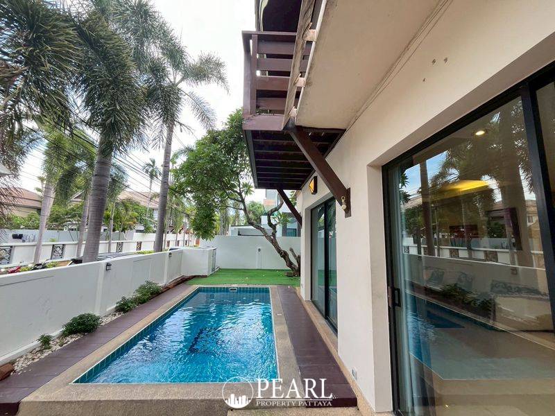 Baan Natcha Village house exterior with private swimming pool, artificial grass, and outdoor dining set.