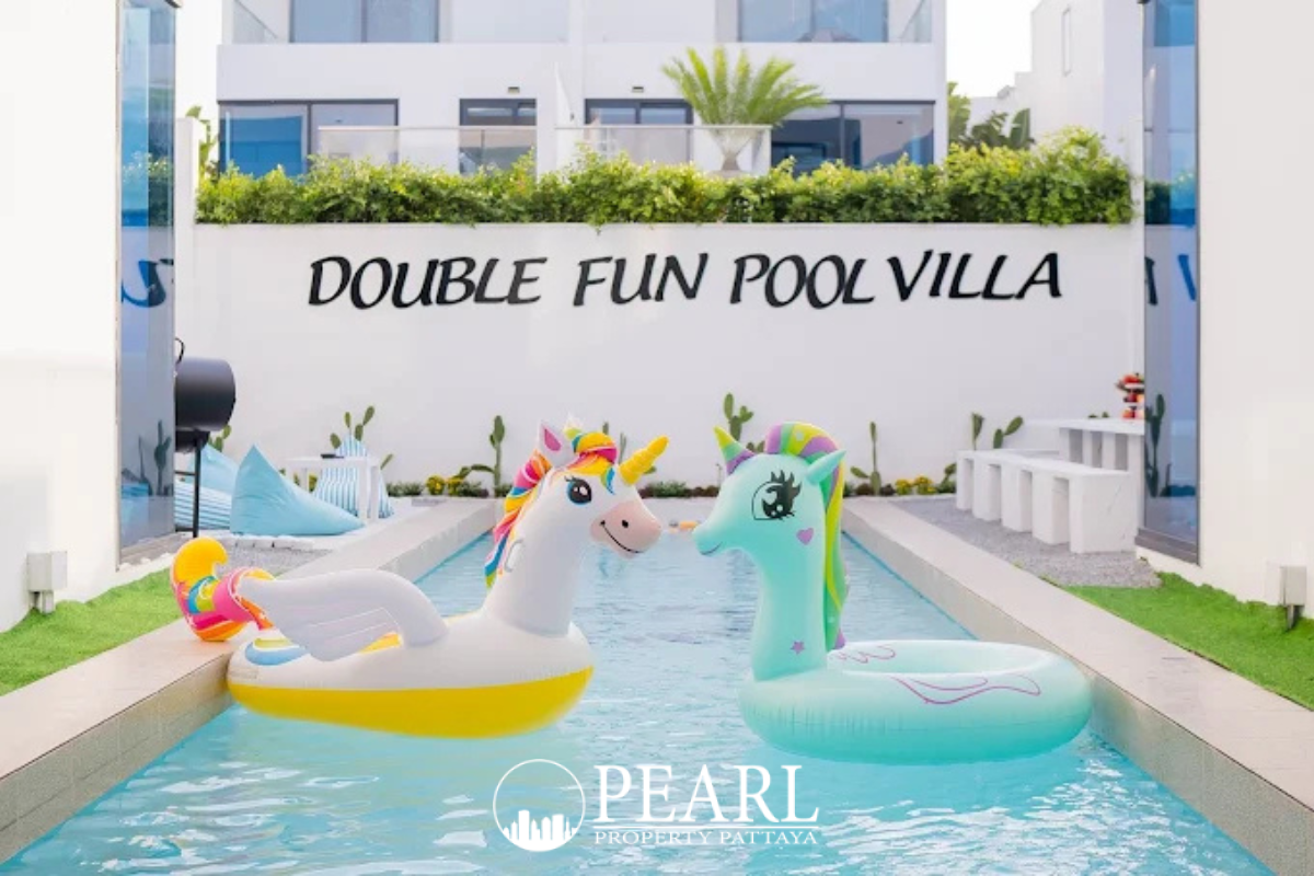 Palm Spring villa Pattaya close-up of a private swimming pool with two large unicorn inflatables and white wall sign.