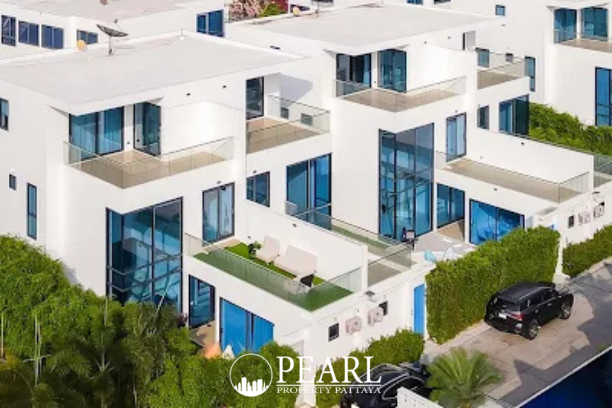Palm Spring villa Pattaya aerial view of modern white villas with glass balconies, lush green landscaping, and a car.