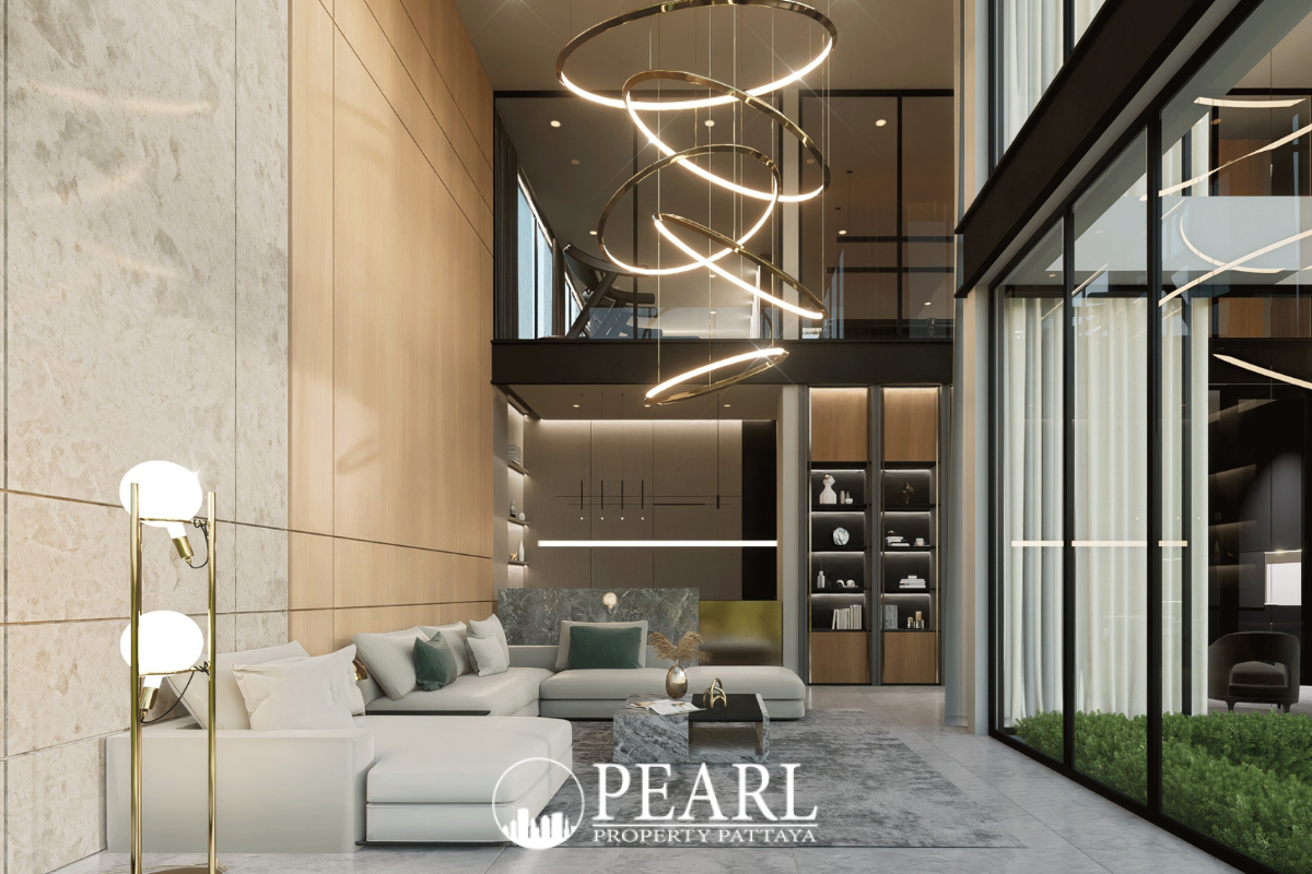 Baan Mae 12 – Onyx Grand Village modern living room with high ceiling, L-shaped sofa, and circular chandeliers.