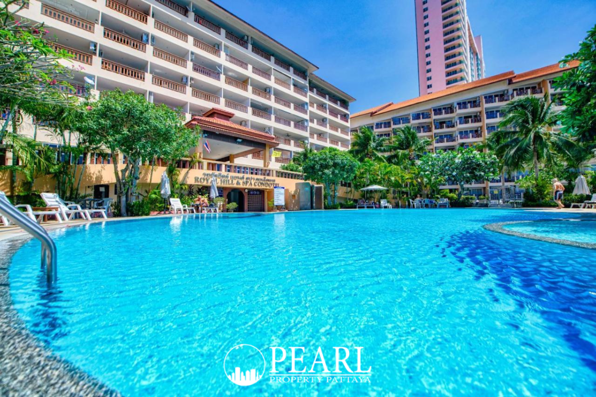 Royal Hill Resort inviting outdoor swimming pool with resort buildings, palm trees, and clear blue water.