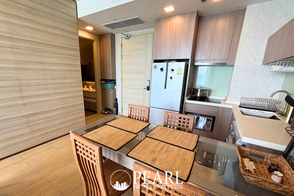 1 Bedroom Condo for Sale at Cetus Beachfront - dining area with glass-top table, wooden chairs, and adjacent kitchen.