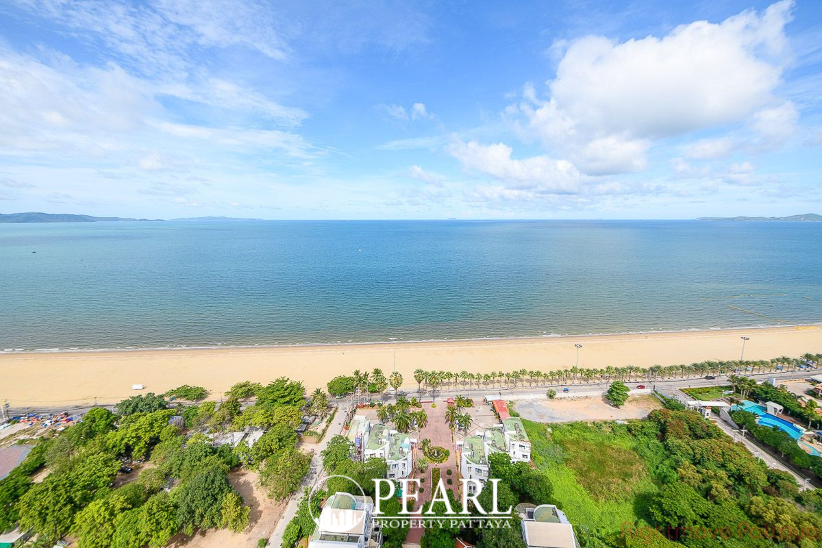 Metro Jomtien Condotel: Large outdoor swimming pool with colorful mosaic patterns and surrounding tropical trees.