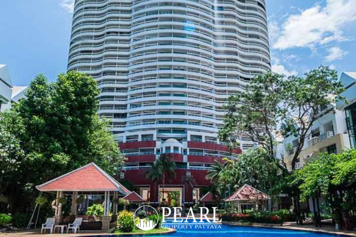 Metro Jomtien Condotel: High-angle view of the long sandy beach, calm ocean, and coastal road under a blue sky.