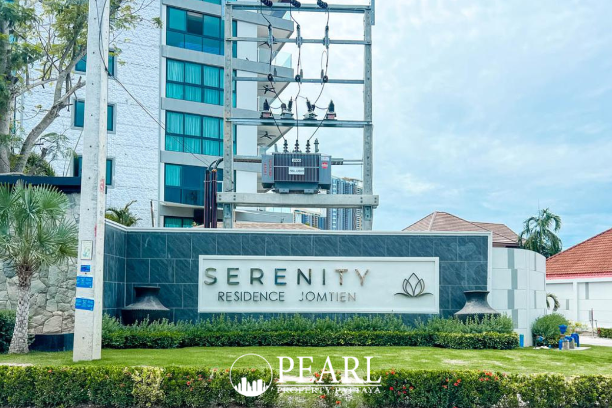 Serenity Residence Jomtien outdoor swimming pool with tiled bottom and the white apartment building facade.